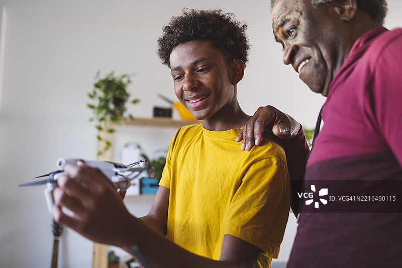微笑的少年在家中向祖父展示无人机图片素材