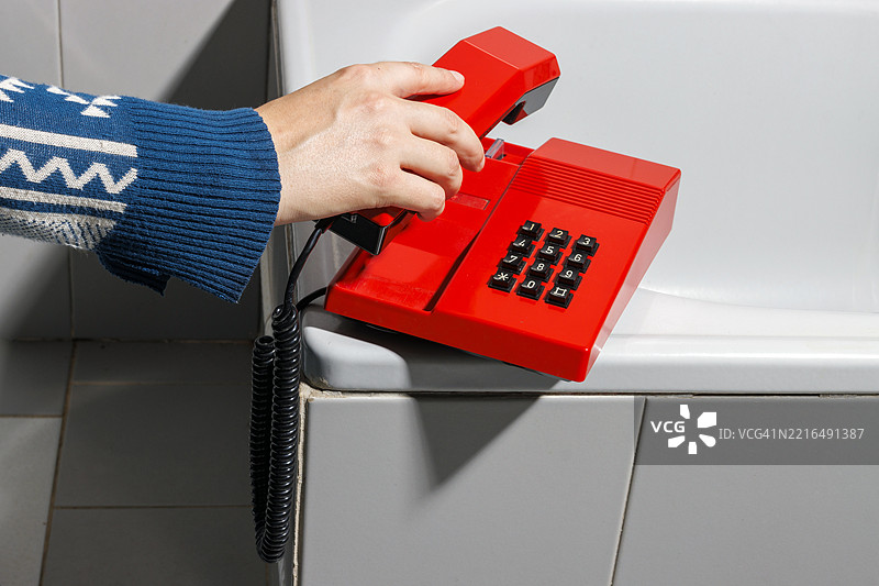 在复古风格的浴室里，拿着红色复古电话的女人图片素材