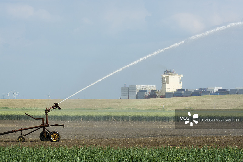 在荷兰泽兰省，农田正在灌溉，一艘集装箱船驶过。图片素材