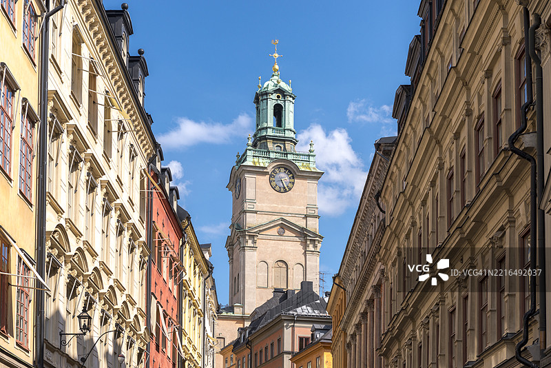 瑞典斯德哥尔摩的历史悠久的圣尼古拉教堂，带有钟楼和时钟，周围环绕着传统建筑。图片素材