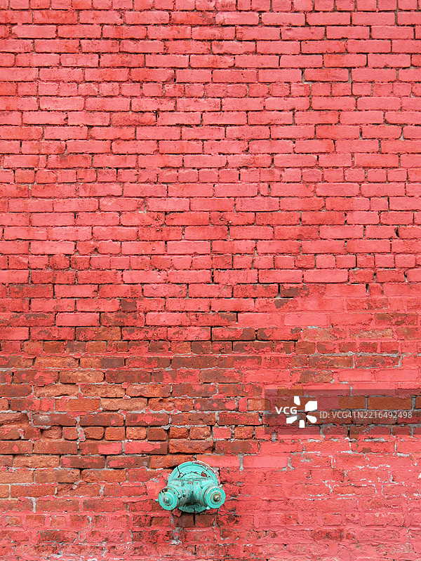 红色涂漆和风化的砖墙上有一个消防立管和喷头。阳光。自然色彩。亨特斯角（长岛市），纽约市，美国。图片素材