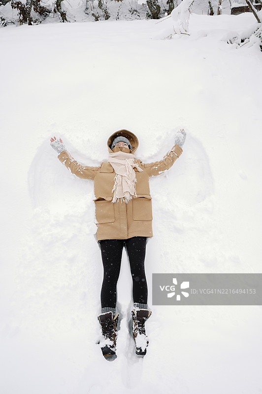 年长的白人女性躺在雪地里，正在冬天制作雪天使图片素材