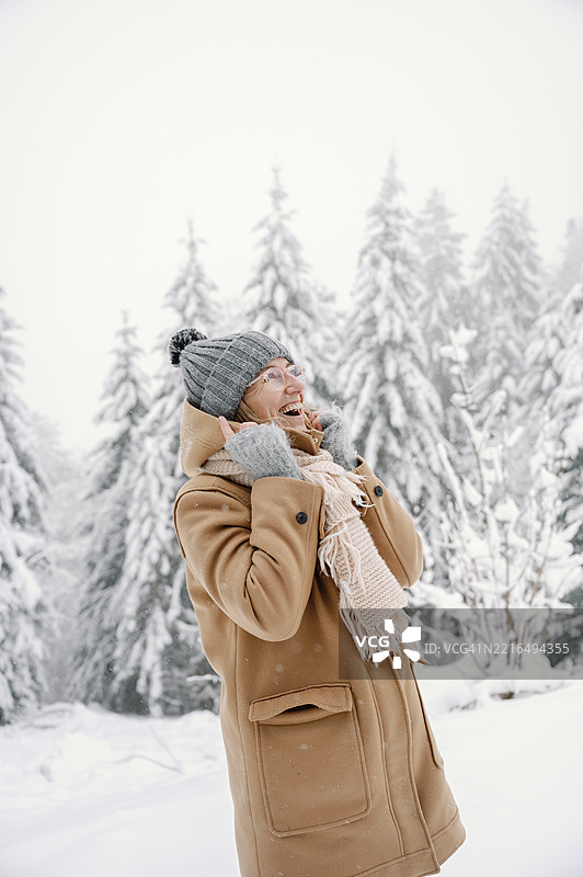 成熟的白人女性在森林中享受雪白的冬日图片素材