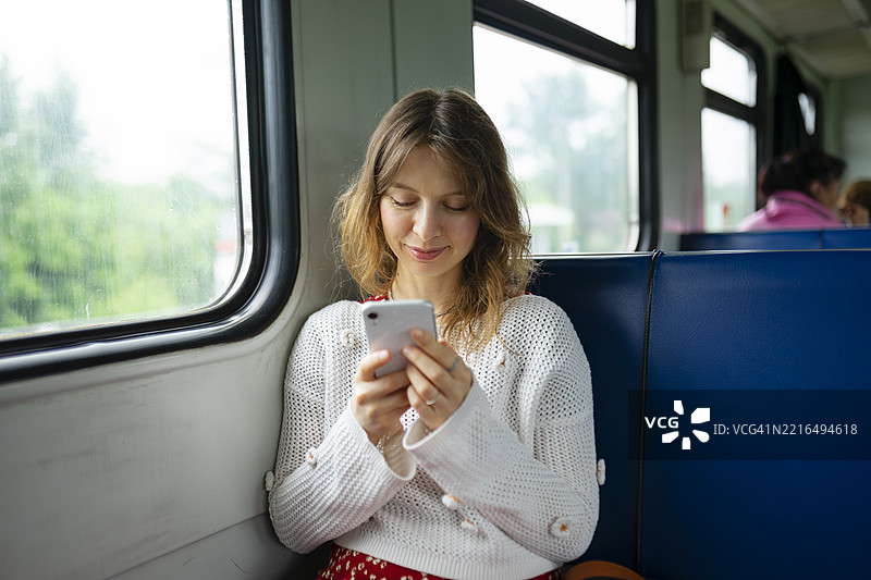 一位中年女性坐在火车上使用手机图片素材