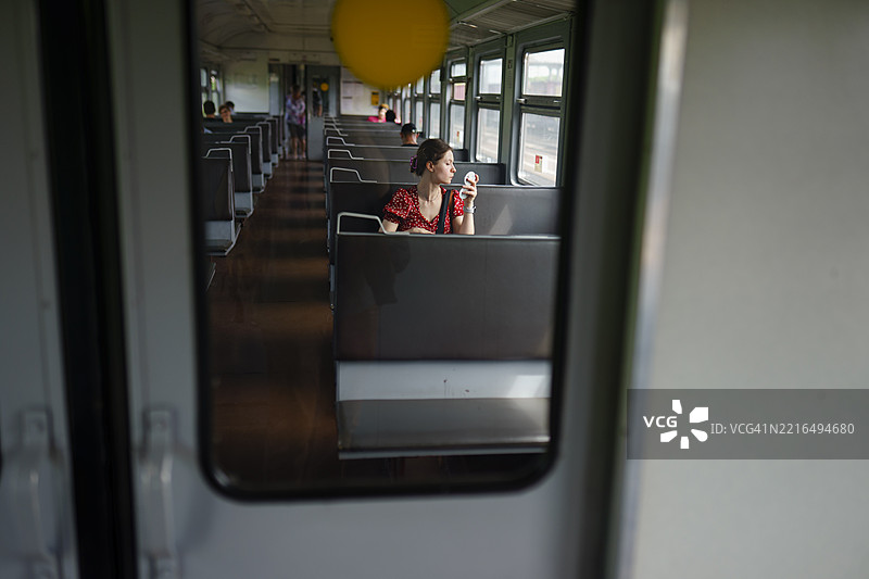 女孩在火车上化妆，坐在车厢里。图片素材