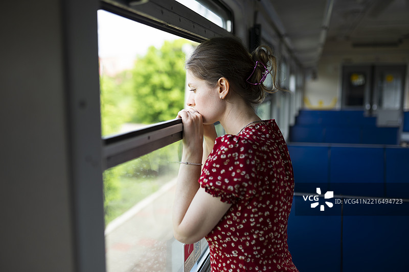 中年女性在阳光明媚的下午旅途中透过火车窗户向外望去图片素材