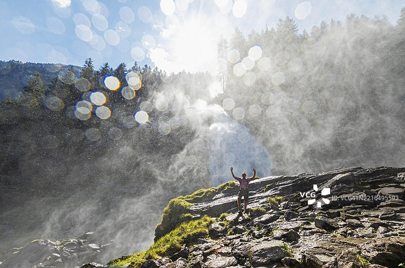 在奥地利萨尔茨堡州的霍赫陶恩国家公园，男子在克里姆尔瀑布的喷雾雾气中欢呼。图片素材