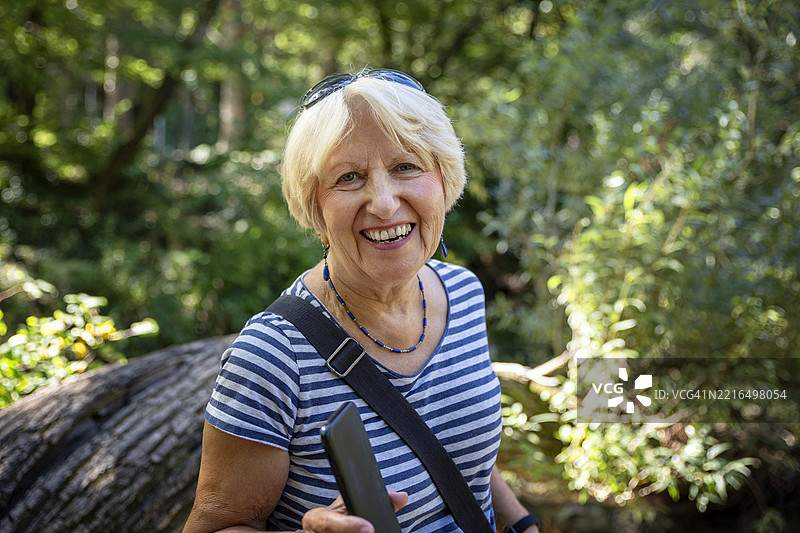 克罗地亚达尔马提亚的切蒂纳山谷中的一位老年女性，笑着拿着智能手机。图片素材