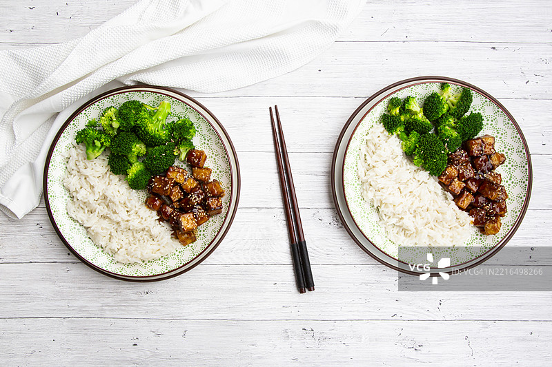 两碗粘豆腐配西兰花和椰子饭，撒上芝麻，摆放在木桌上图片素材