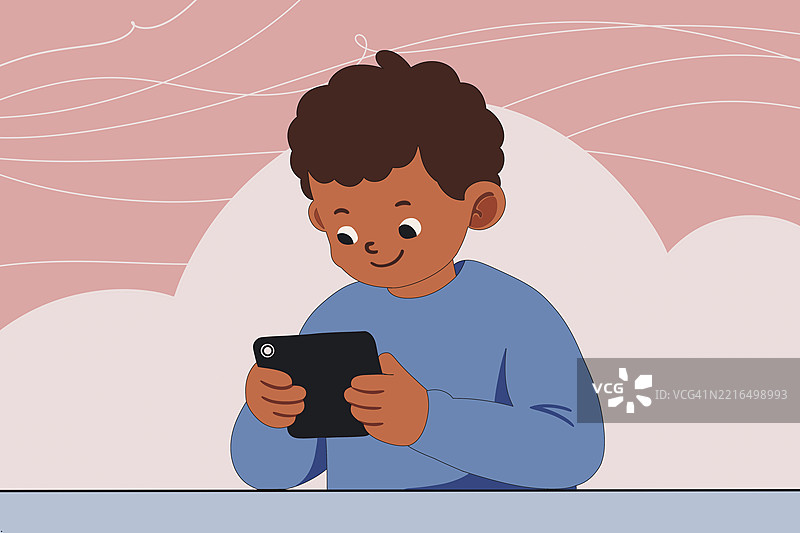 微笑的男孩在桌子上使用智能手机图片素材