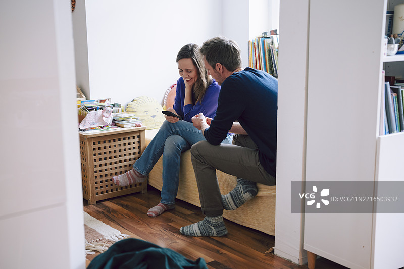 一对情侣坐在家中交谈并查看智能手机图片素材