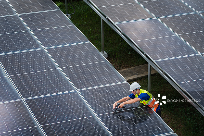 工程师使用电钻对太阳能面板结构进行维护图片素材