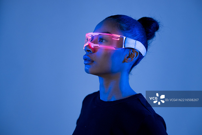佩戴虚拟现实眼镜的人，身处未来风格的工作室，蓝色灯光照耀。图片素材