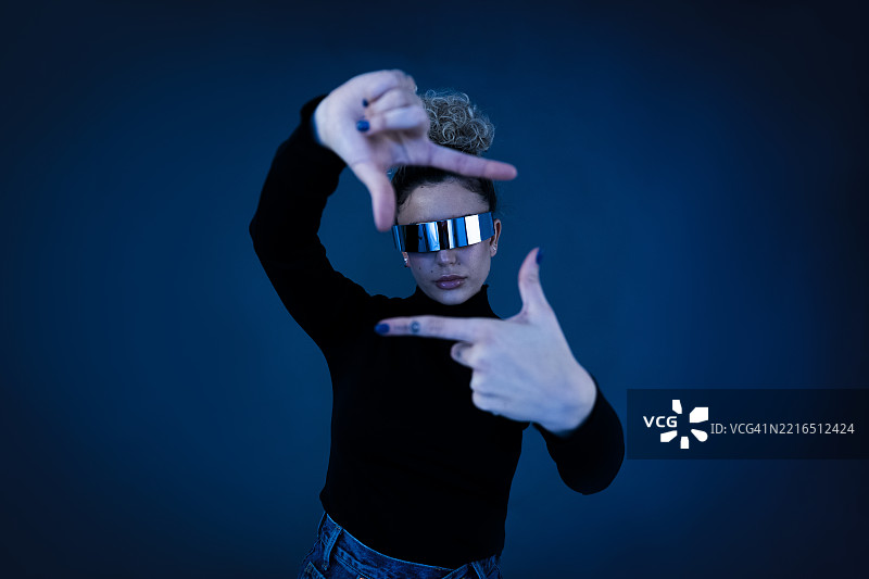 戴着虚拟现实眼镜的卷发人正在未来主题的工作室中摆姿势图片素材