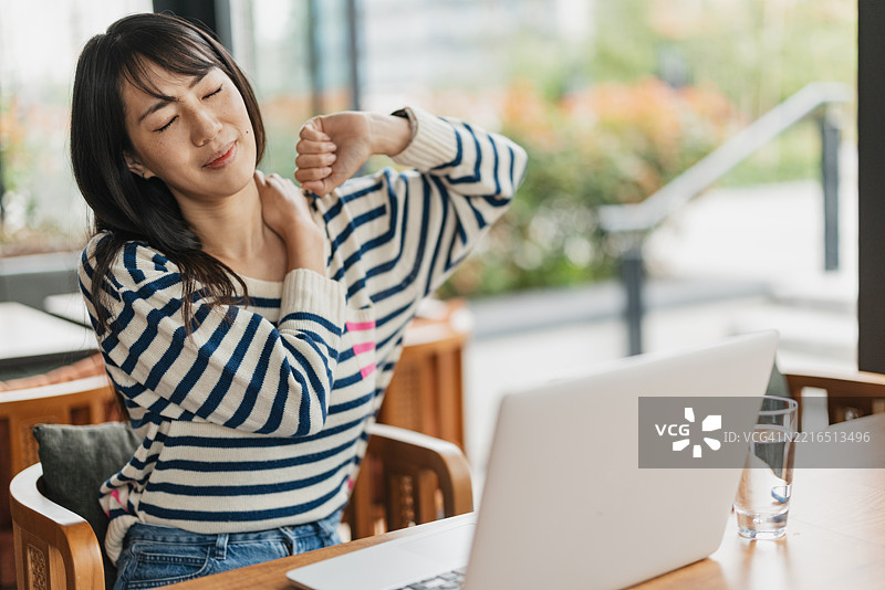 女性在笔记本电脑前工作了很长时间后伸展身体图片素材