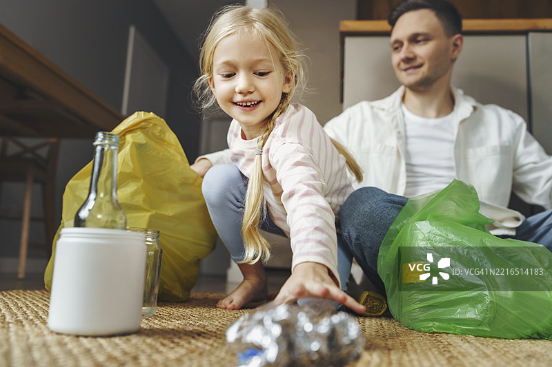 父亲和女儿在家中分类垃圾以便回收图片素材