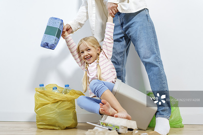 父亲和女儿在家中分类垃圾，关注可持续发展和回收利用图片素材