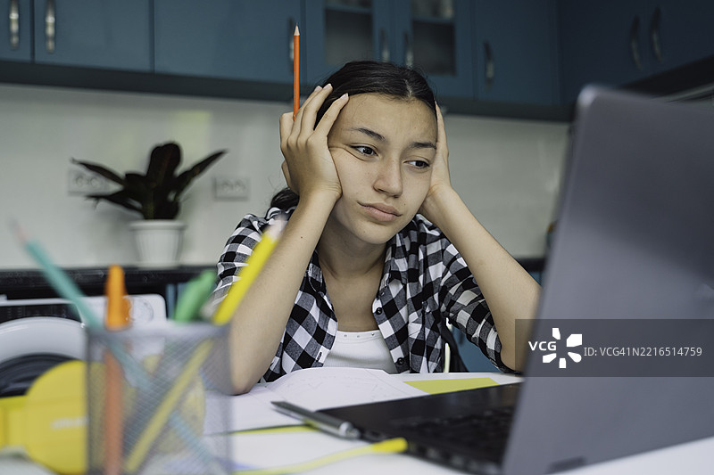 沮丧的女孩盯着笔记本电脑学习图片素材