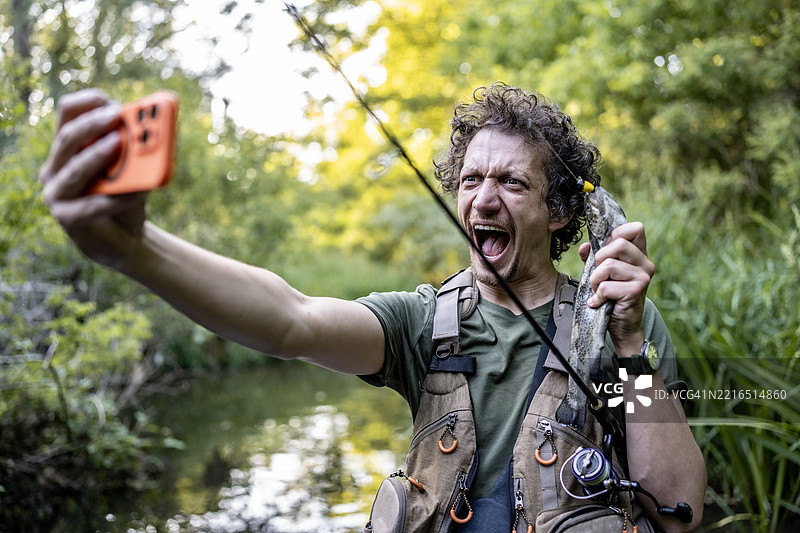 男子在风景如画的自然环境中兴奋地与鱼自拍图片素材