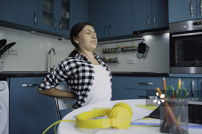 女孩在学习时因背痛而挣扎图片素材