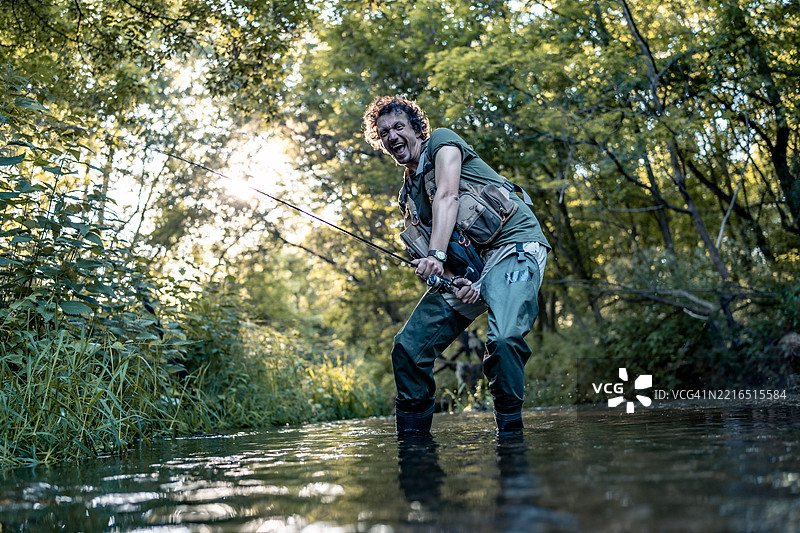 男人在森林小溪中享受日落时的钓鱼时光图片素材