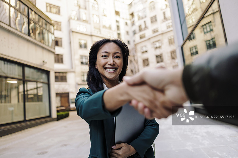 在城市环境中，微笑的女商人与人握手图片素材