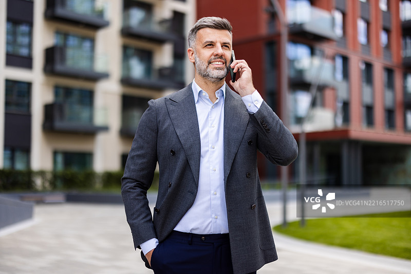 自信的企业家在城市中心随时接听工作电话图片素材