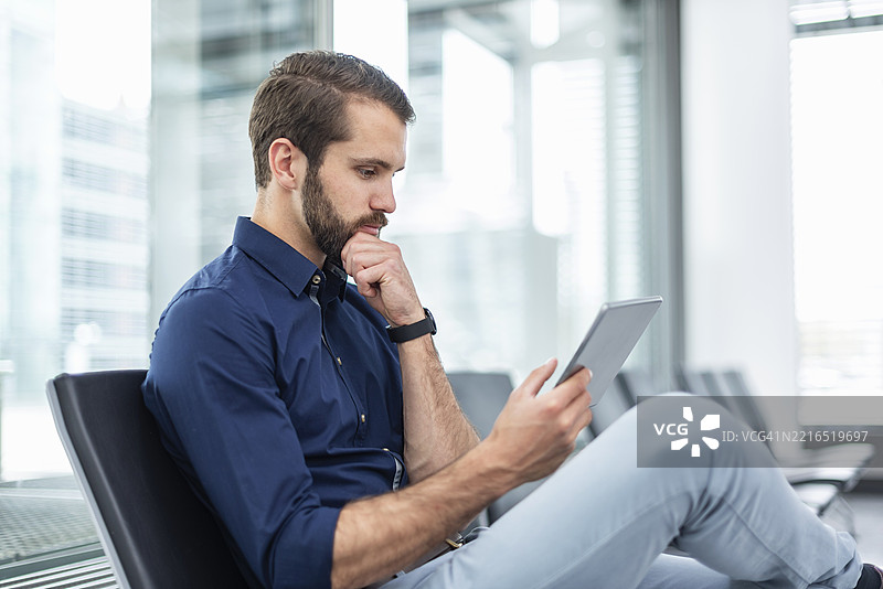 办公室里的商人坐着看平板电脑图片素材