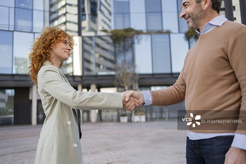 商业伙伴在办公大楼前户外握手图片素材