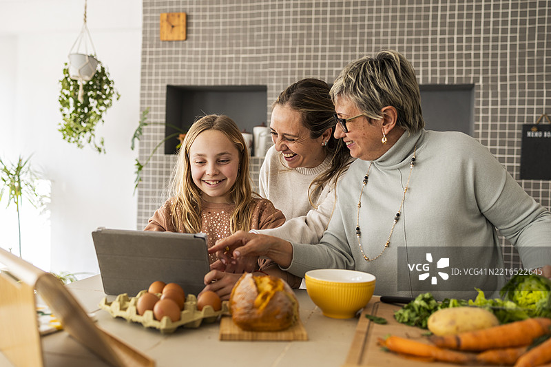 一家人在厨房里一起用平板电脑做饭图片素材