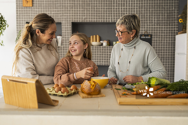 一家人在厨房里一起用平板电脑做饭图片素材