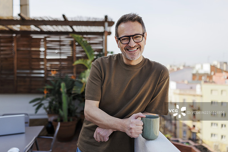 男子在屋顶露台上享受咖啡休息时光图片素材