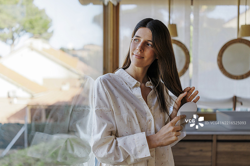 女人在浴室里梳头，进行早晨日常护理图片素材