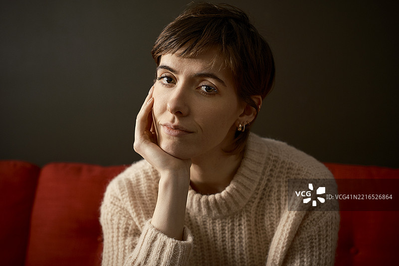 一位女性坐在伦敦的沙发上，面带担忧的表情看着镜头。图片素材