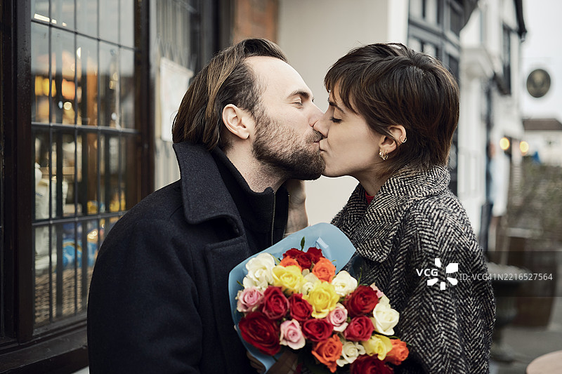 在伦敦街头亲吻的情侣，手中捧着一束花。图片素材