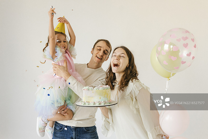 家庭在室内庆祝生日，享用蛋糕和气球图片素材