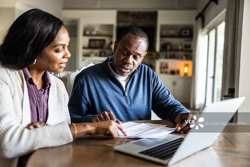 夫妻在家中的厨房查看账单并使用笔记本电脑图片素材