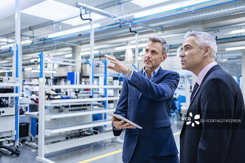 高管在生产大厅讨论战略，手持平板电脑图片素材