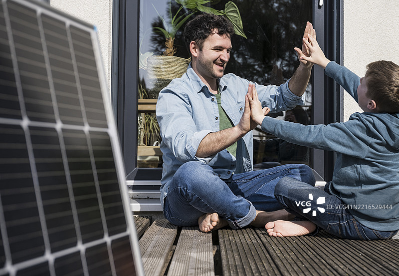 父亲和儿子在户外享受高质量的亲子时光，旁边有一个太阳能电池板图片素材