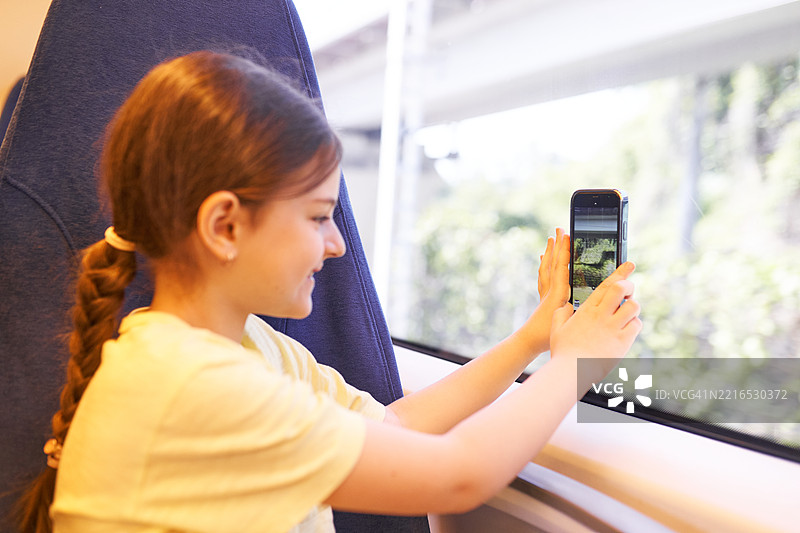 年轻女孩用手机从火车窗外拍照图片素材