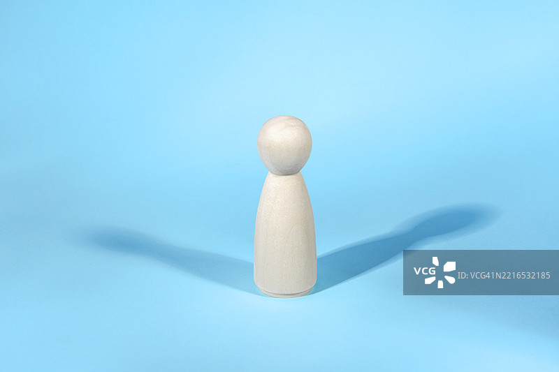 蓝色背景上的木质雕像与两个阴影的抽象概念图片素材