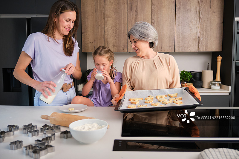 祖母、母亲和女儿在厨房里烤饼干并喝牛奶图片素材