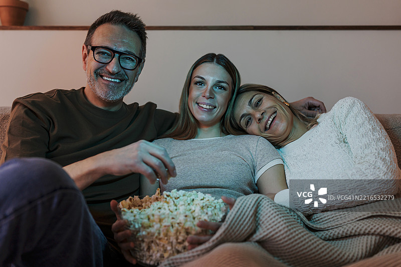 一家人在家享受温馨的电视观看时光图片素材