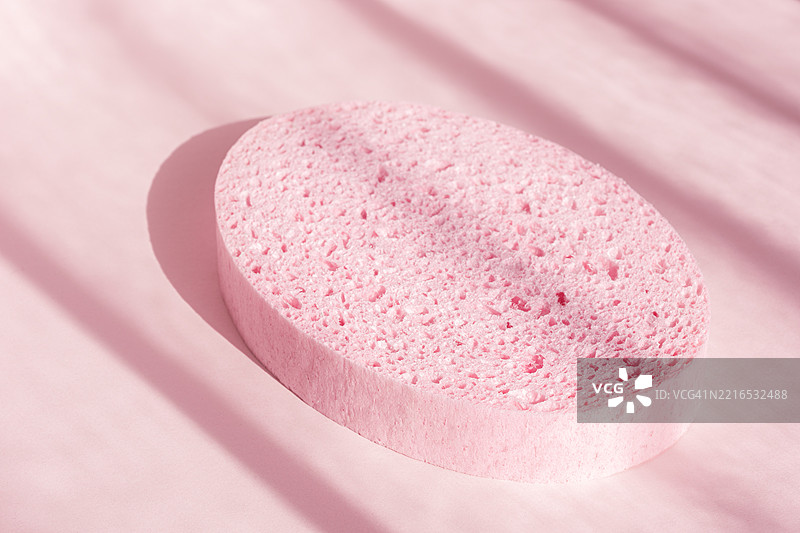 粉色阴影背景上的浴海绵 椭圆形水疗淋浴擦洗配件图片素材