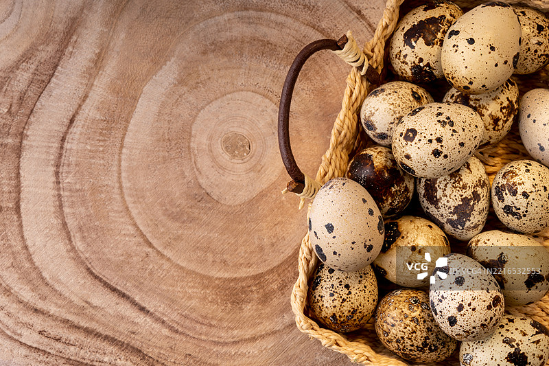 柳条篮中的鹌鹑蛋，放在木纹切割的质感上，展现出乡村风格。图片素材