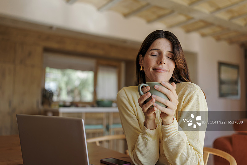 女性在家中享受温暖饮品，享受远程工作间歇时光图片素材