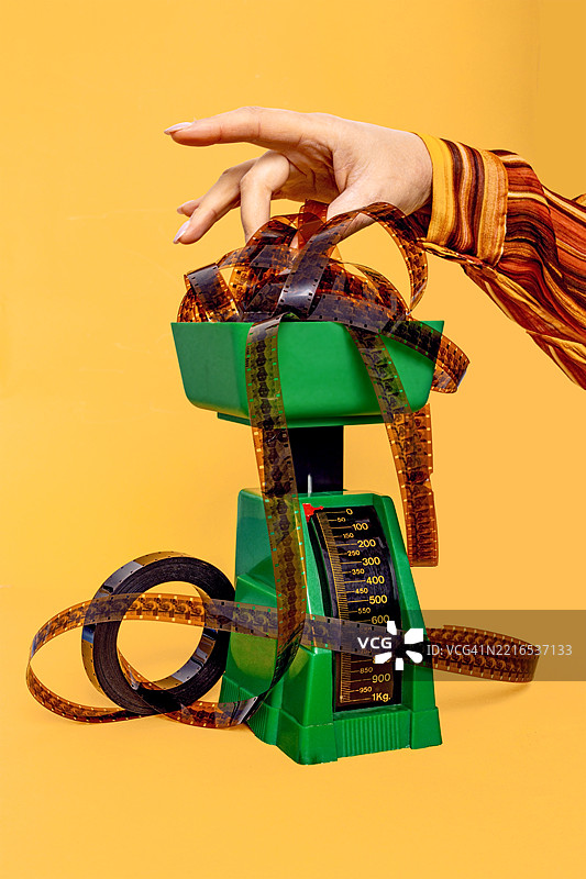 复古食品秤与负片胶卷和手在黄色背景上图片素材