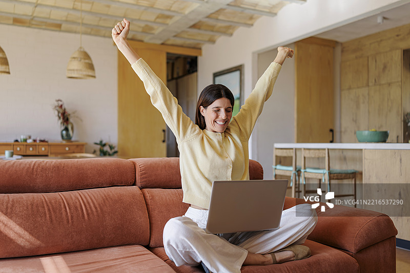 在家用笔记本电脑工作的女商人庆祝成功图片素材
