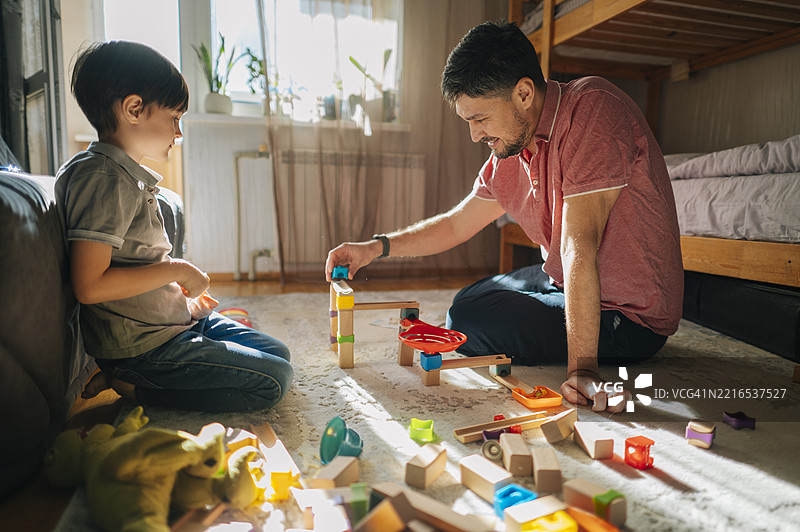 父亲和儿子在家里白天玩积木图片素材