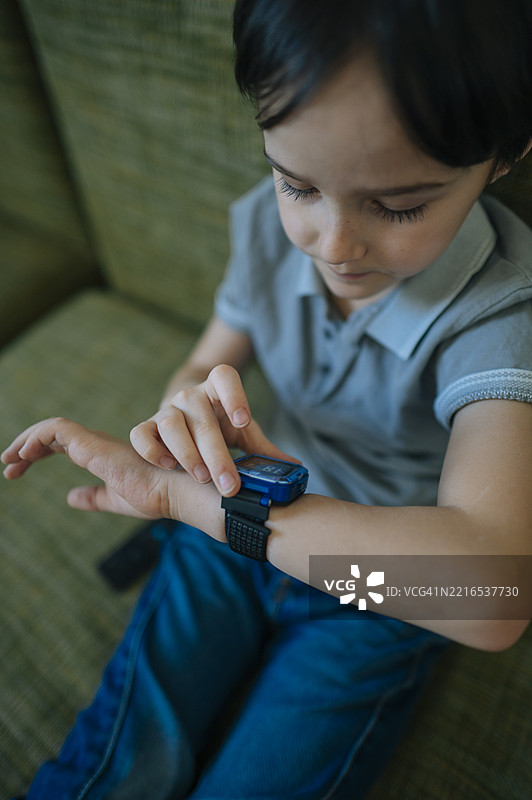 男孩在室内与智能手表互动图片素材